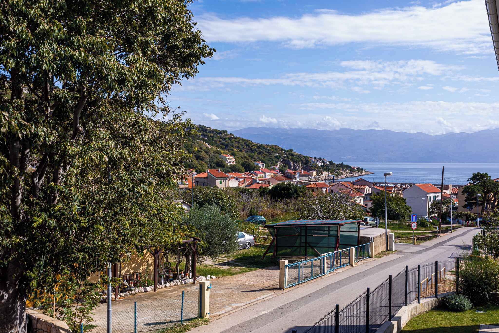 A coastal town with houses, a road, and a bus stop.