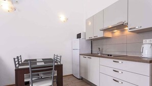 A compact kitchen with white cabinets, a microwave, a refrigerator, and a coffee maker. - Holiday apartment with a balcony and sea view (Baška)