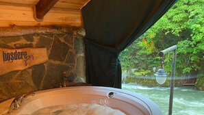 Un jacuzzi de madera con una pared de piedra y un letrero que dice "hosdere".
