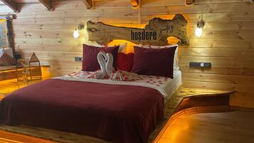 Un dormitorio de cabaña de madera con cama, almohadas y una lámpara fijada a la pared.