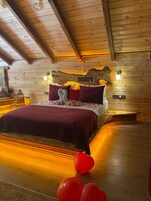 Un dormitorio de cabaña de madera con cama, almohadas y una lámpara fijada a la pared.
