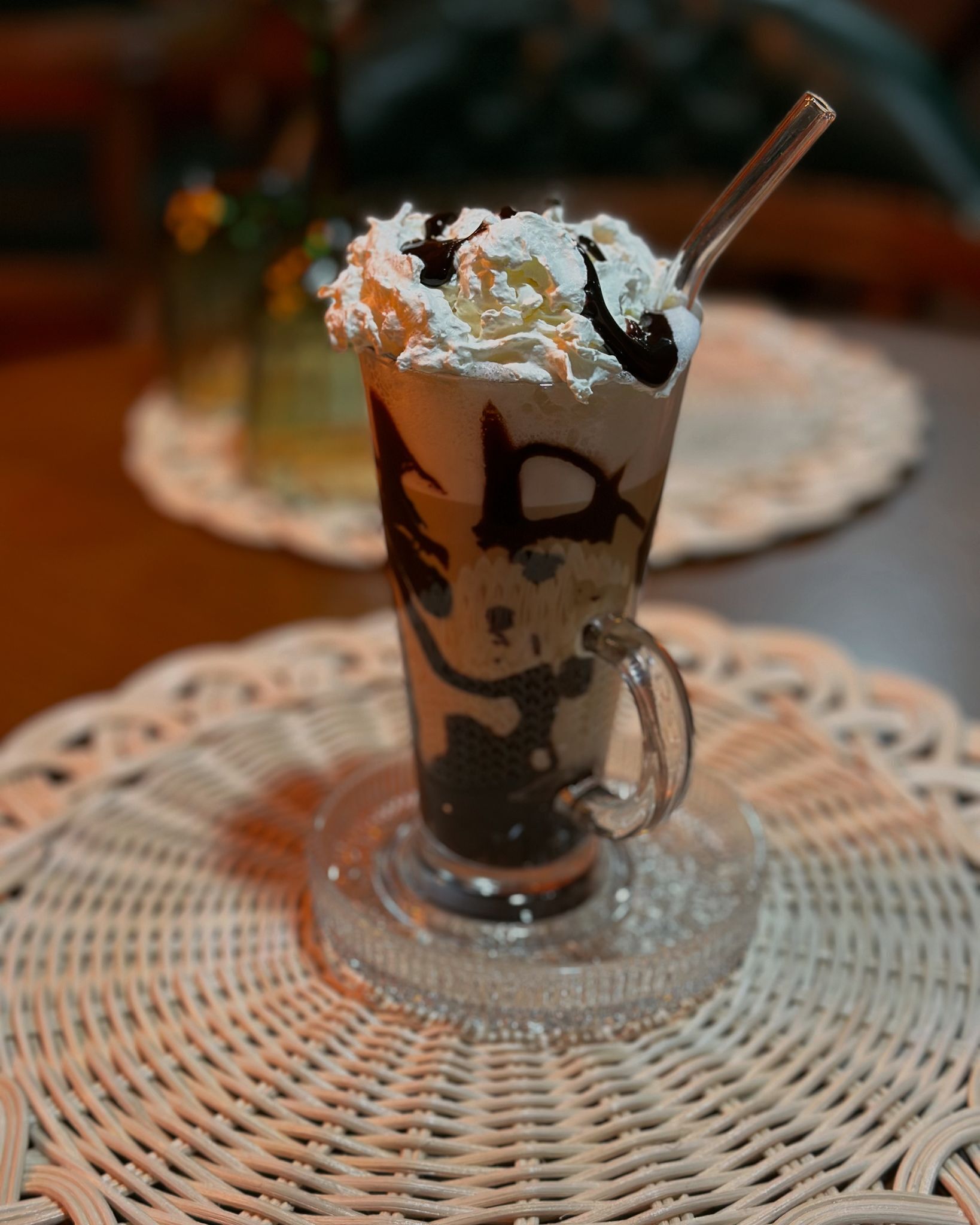 A dessert in a glass with a straw, placed on a doily.