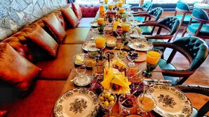 Un bufé de desayuno con una variedad de alimentos y bebidas, una pared de piedra y una zona de estar con sofás y sillones de cuero.