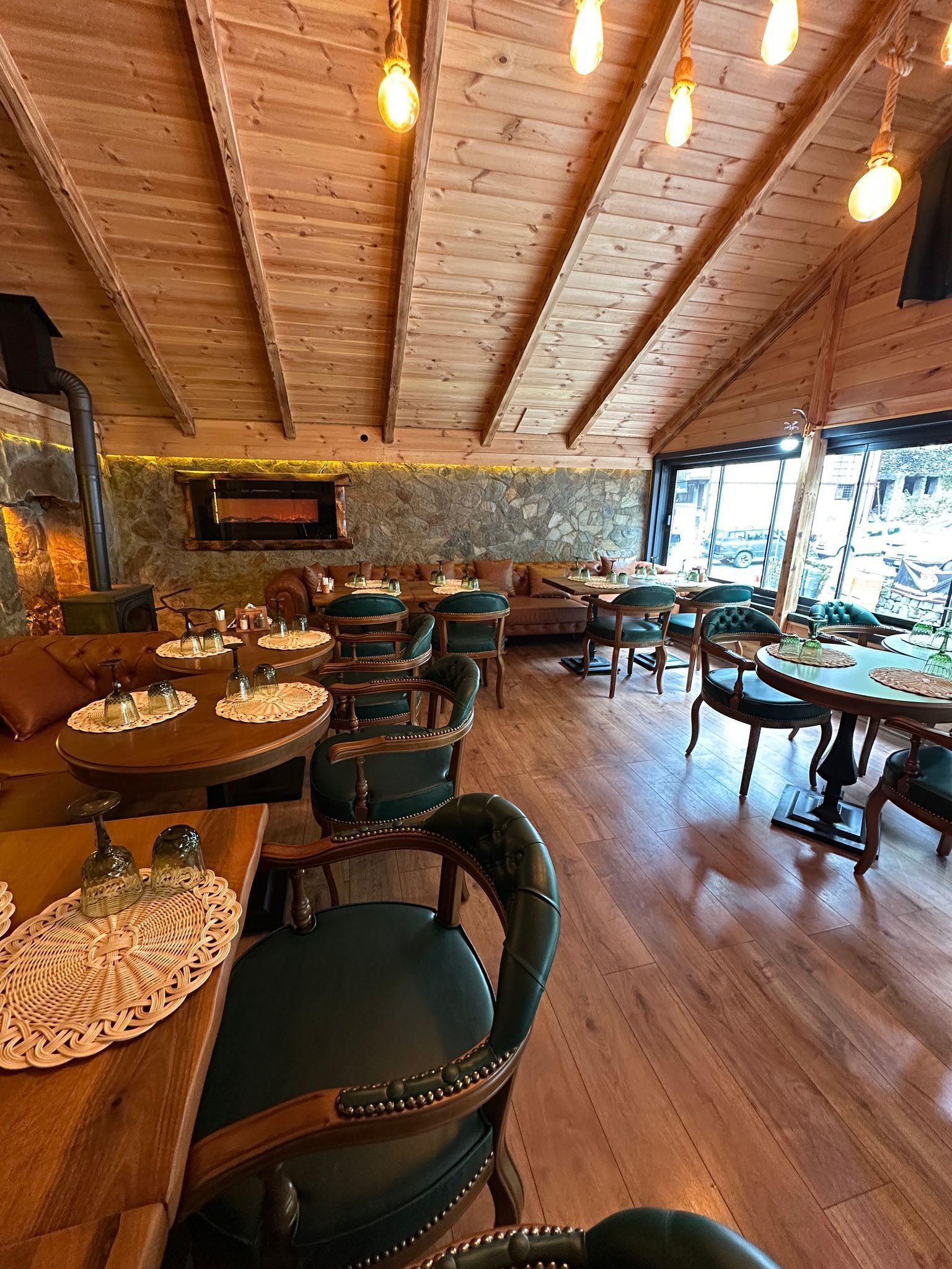 Ein gemütliches Restaurant mit Holzbalkendecken und Steinwänden. Tische und Stühle sind zum Essen angeordnet.