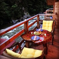 Una terraza de madera con una mesa preparada para dos, con vista a un río.