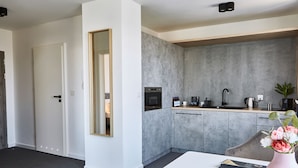 A modern kitchen with a grey backsplash, white cabinetry, and a built-in oven. - Silesia Apartments (Katowice)