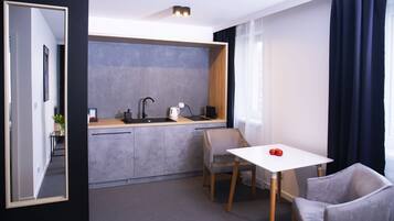 A modern kitchen with a sink, stove, and countertop. There is a small table with two chairs and a single red apple on it.
