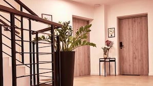 A modern interior with a staircase, a potted plant, and a door. - Silesia Apartments (Katowice)