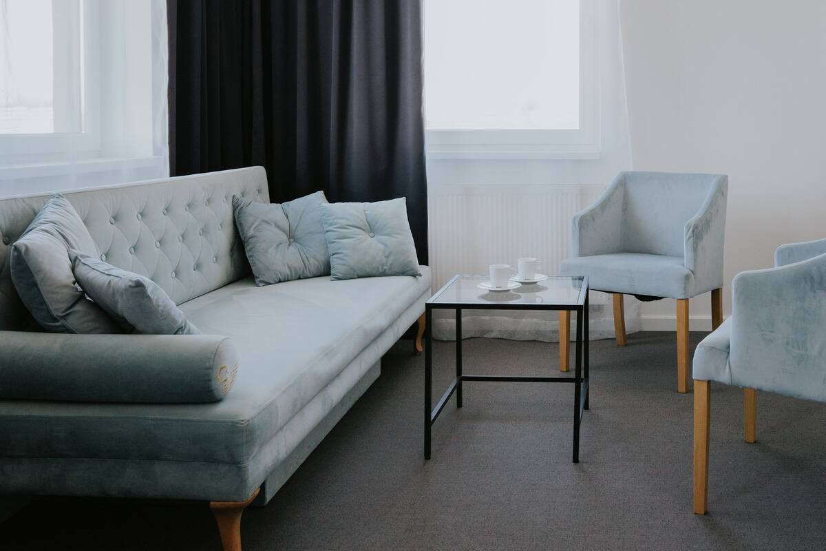 A modern living room with a grey sofa, two armchairs, and a small table.