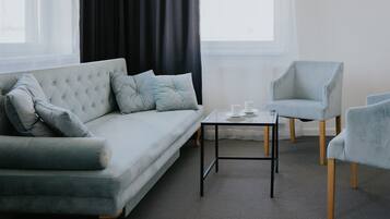 Un salon moderne avec un canapé gris, deux fauteuils et une petite table.