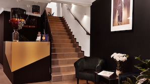 A modern hotel lobby with a staircase, a reception desk, and a seating area. - Silesia Apartments (Katowice)