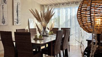 Een eethoek met een houten plafond, rieten stoelen, een ronde tafel en een kroonluchter.