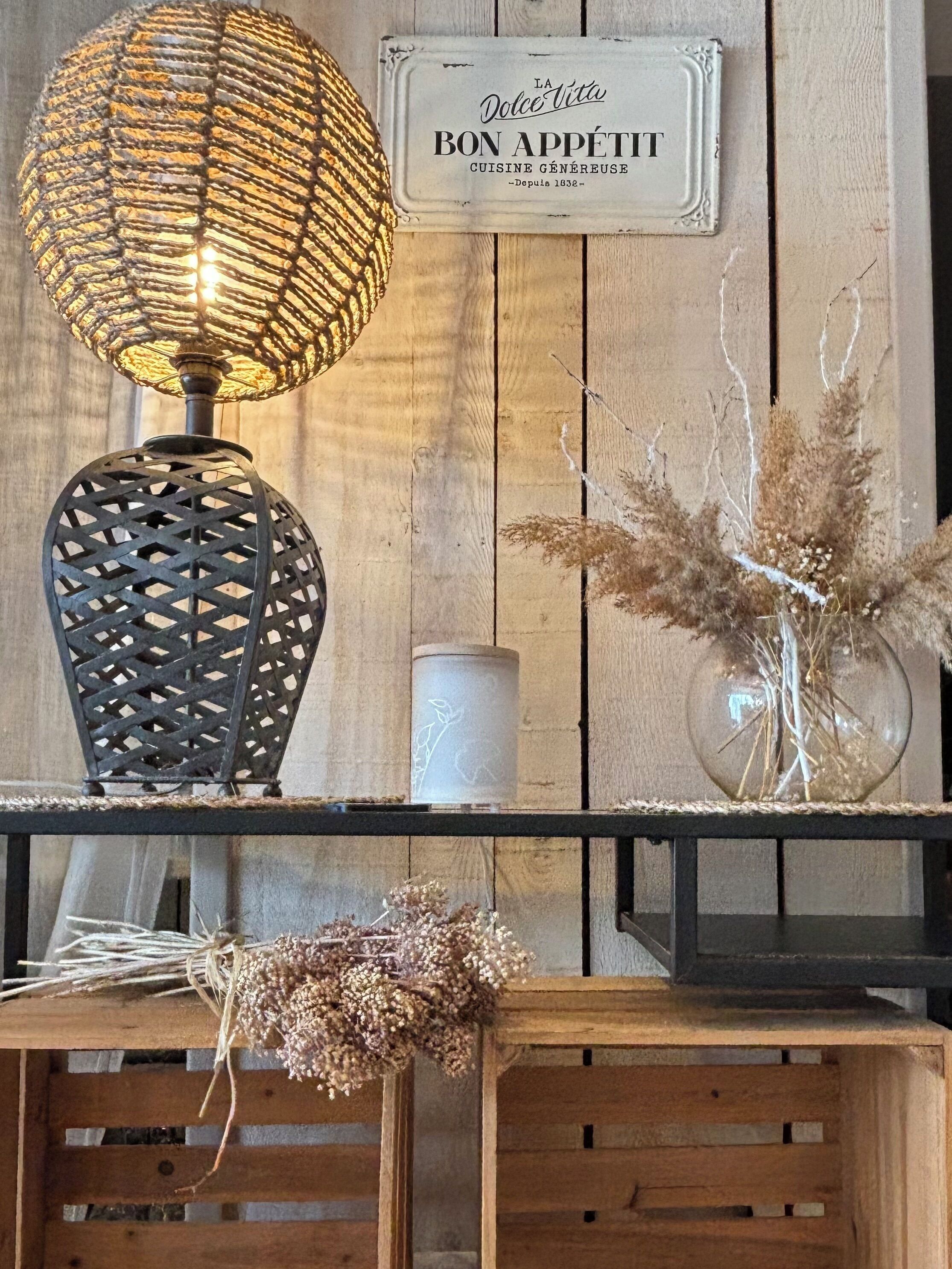 Une étagère en bois rustique, agrémentée d’une lampe décorative, d’une bougie et de fleurs séchées.