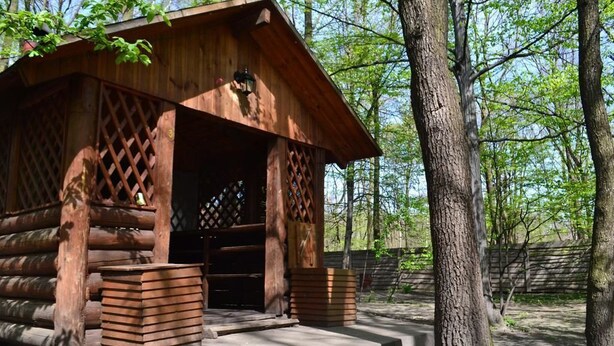 Une cabane en bois rustique, dotée d’une porte à treillis et d’un petit espace porche.