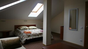 Une chambre avec une lucarne, un lit avec des oreillers, une table de chevet et un miroir au mur.