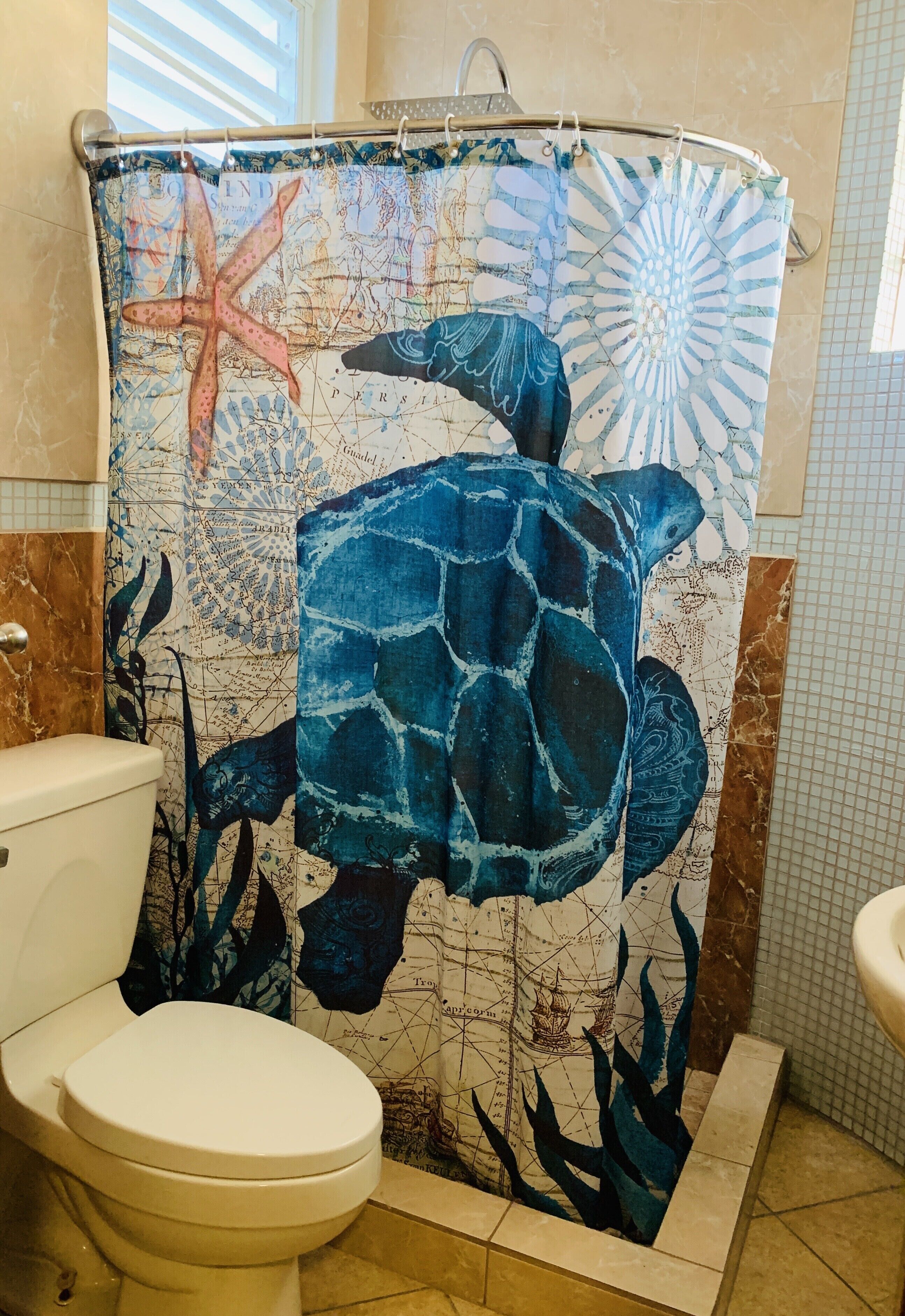 Une salle de bain équipée d’un rideau de douche orné d’un motif de tortue de mer, de toilettes et d’un lavabo.