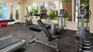 Une salle de sport équipée de tapis de course, de vélos elliptiques et de matériel de musculation.