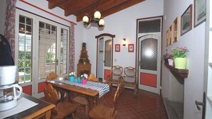 A dining area with a wooden table, chairs, a coffee machine, and a chandelier. - Villa Schiller (Lignano Sabbiadoro)