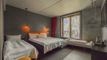 Habitación de hotel con dos camas, una ventana con vista a una noria, una pequeña zona de estar y una kitchenette.