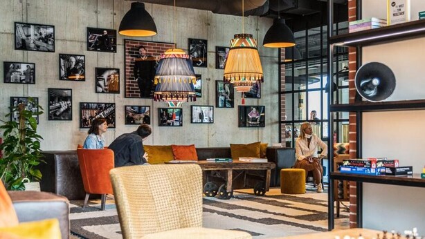 A modern lounge area with seating, a chess table, and a bookshelf.