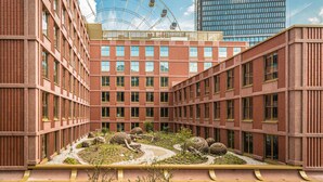 A modern building with a central courtyard featuring spherical sculptures and a Ferris wheel in the background.