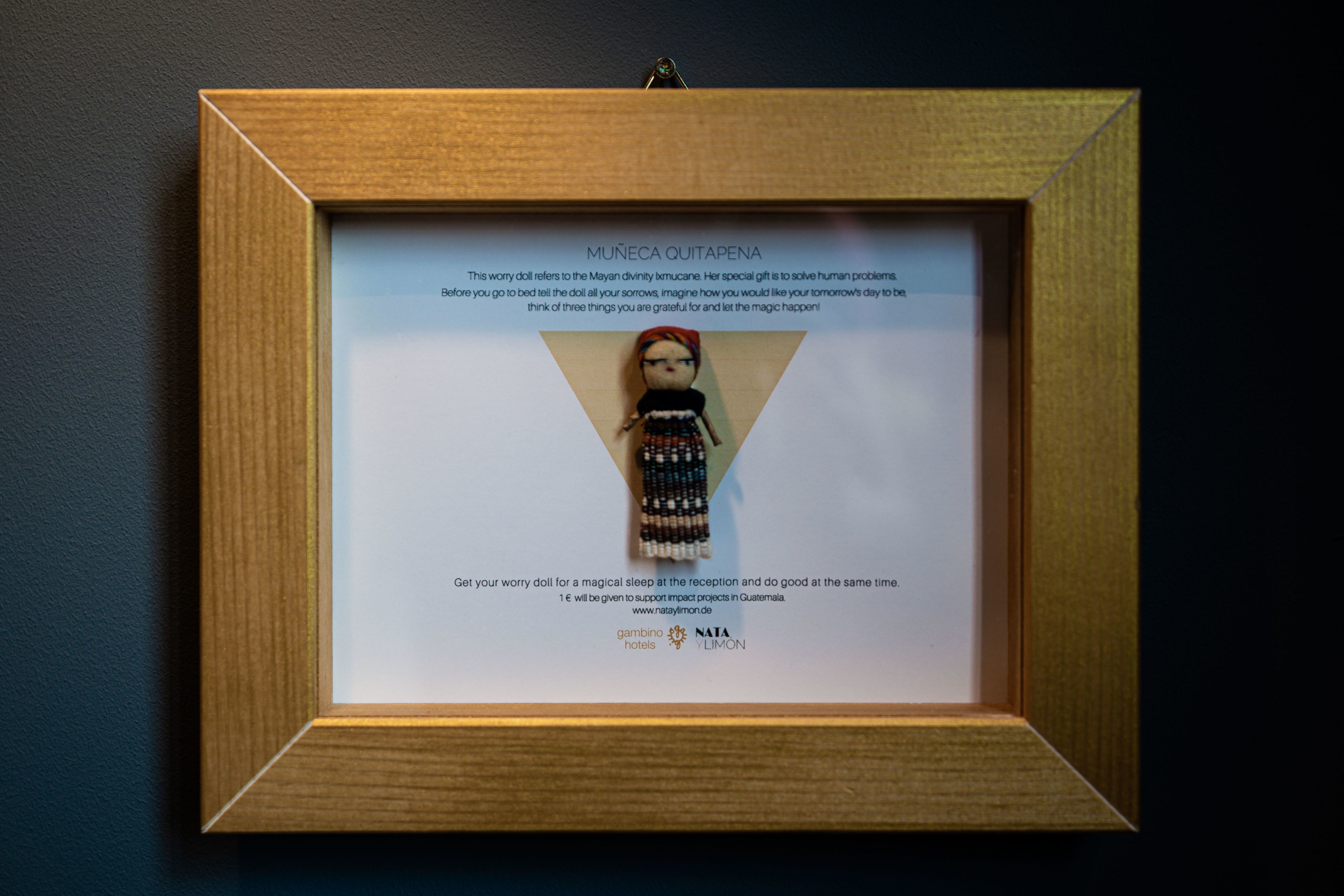 A framed worry doll with a description and a donation request for Guatemala.