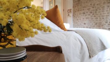 A bed with white bedding, a brown pillow, and a yellow flower arrangement on a bedside table.