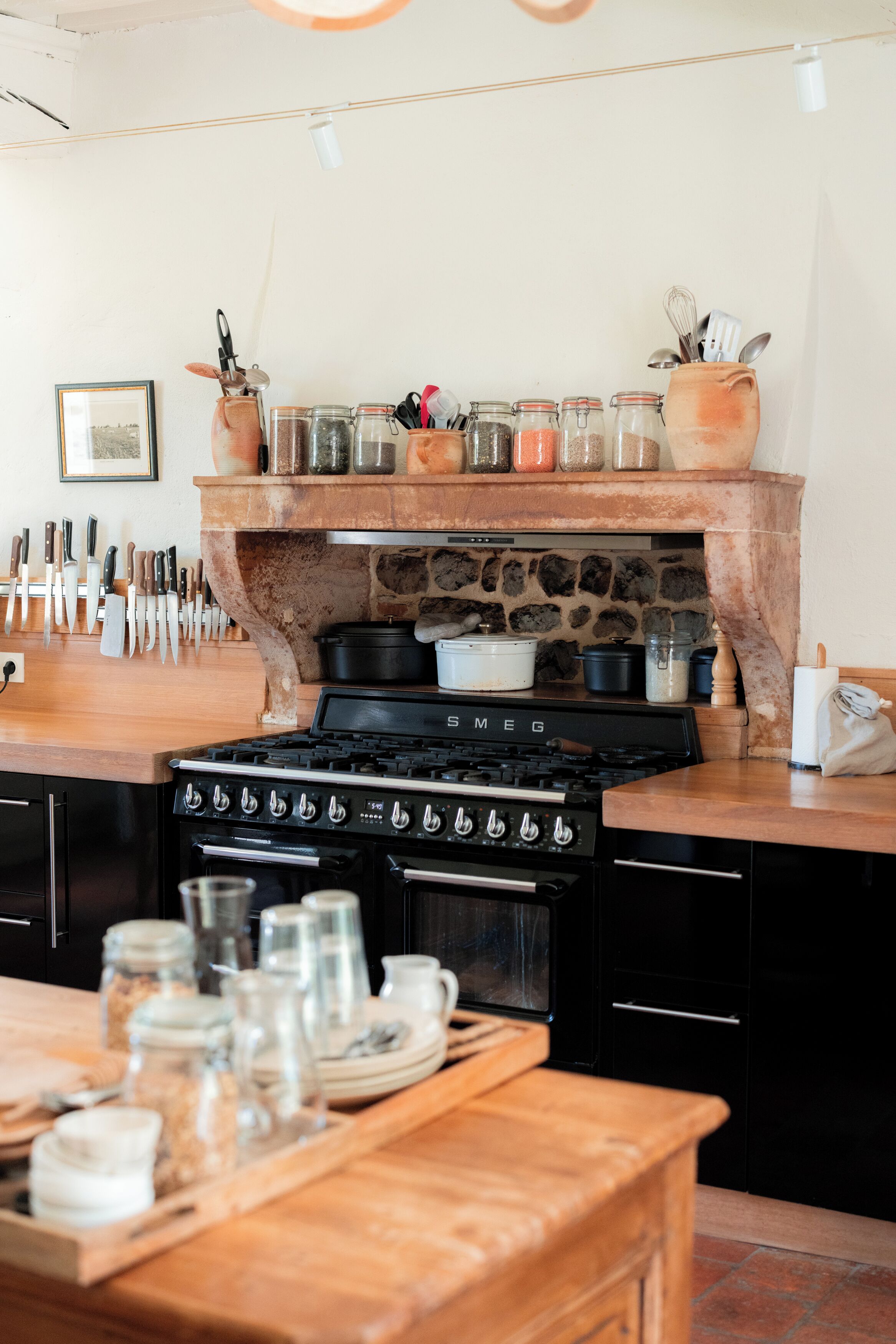 Una cocina con chimenea de piedra, estufa y diversos utensilios.