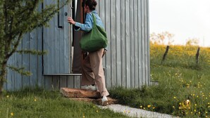 Una persona entrando en una construcción de madera con una puerta y un ventanal pequeño.