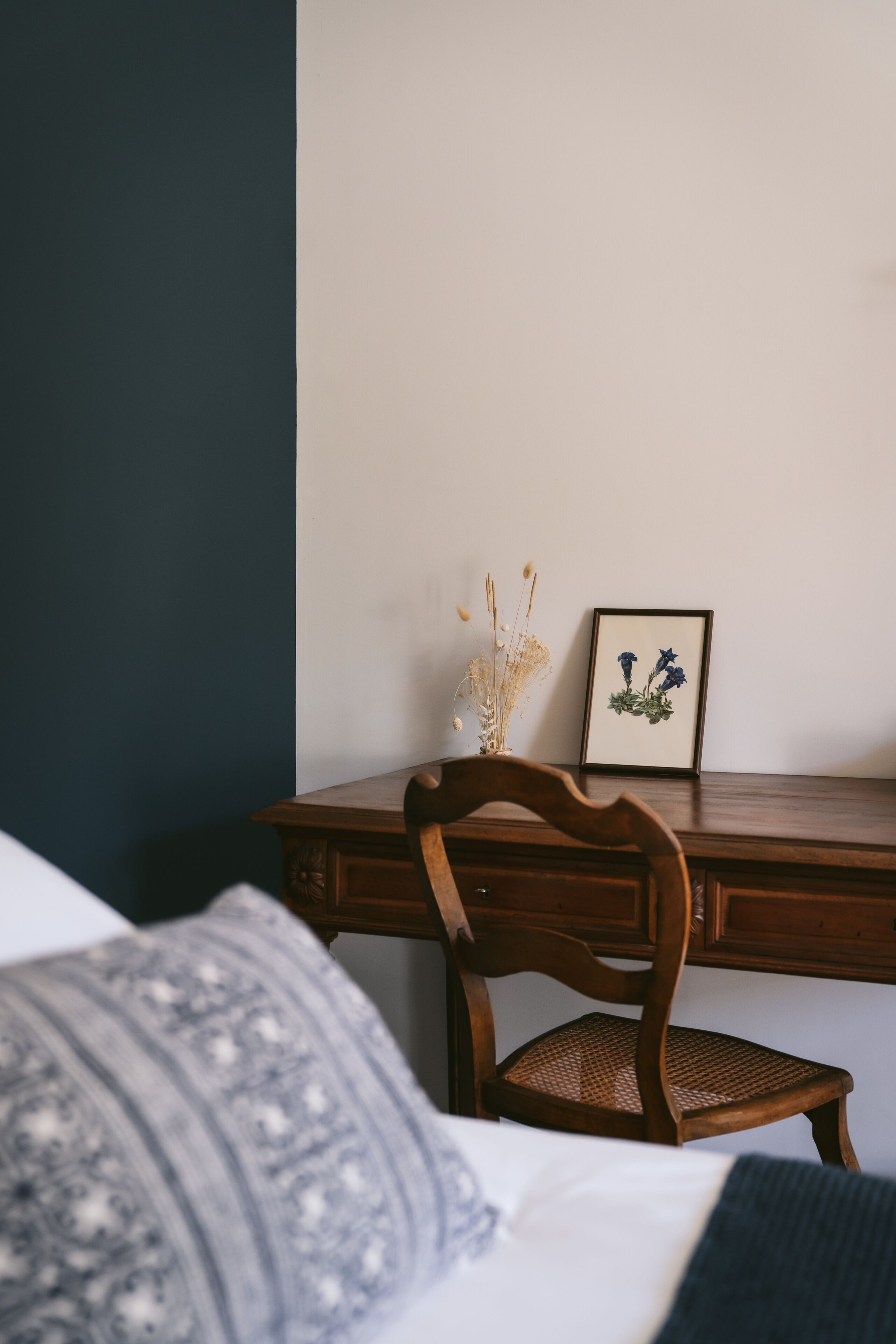 Ein Schlafzimmer mit einem Holztisch, einem gerahmten Bild und einem Stuhl.