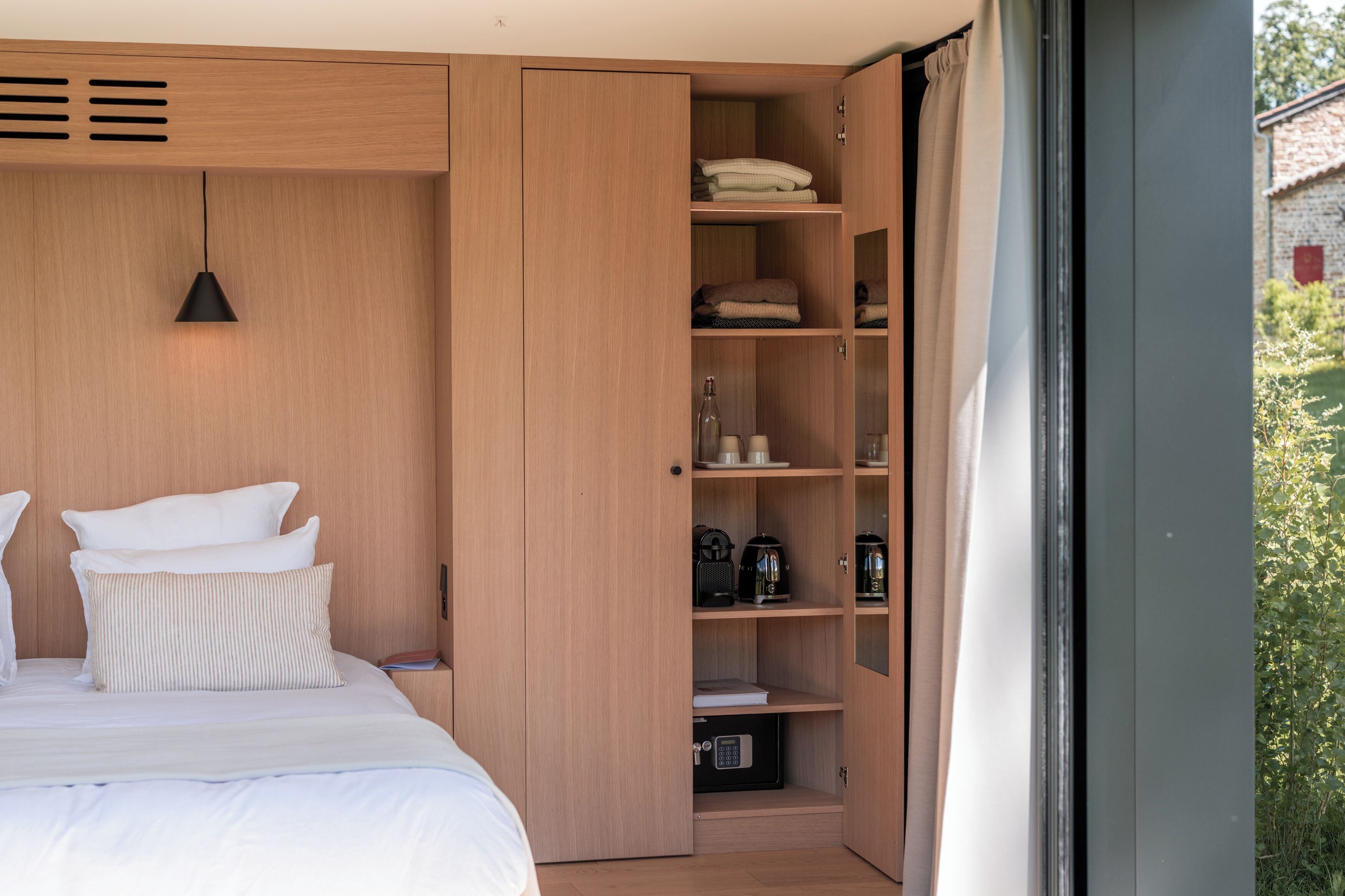 Un dormitorio con cama, armario y ventana con vista a zonas verdes.