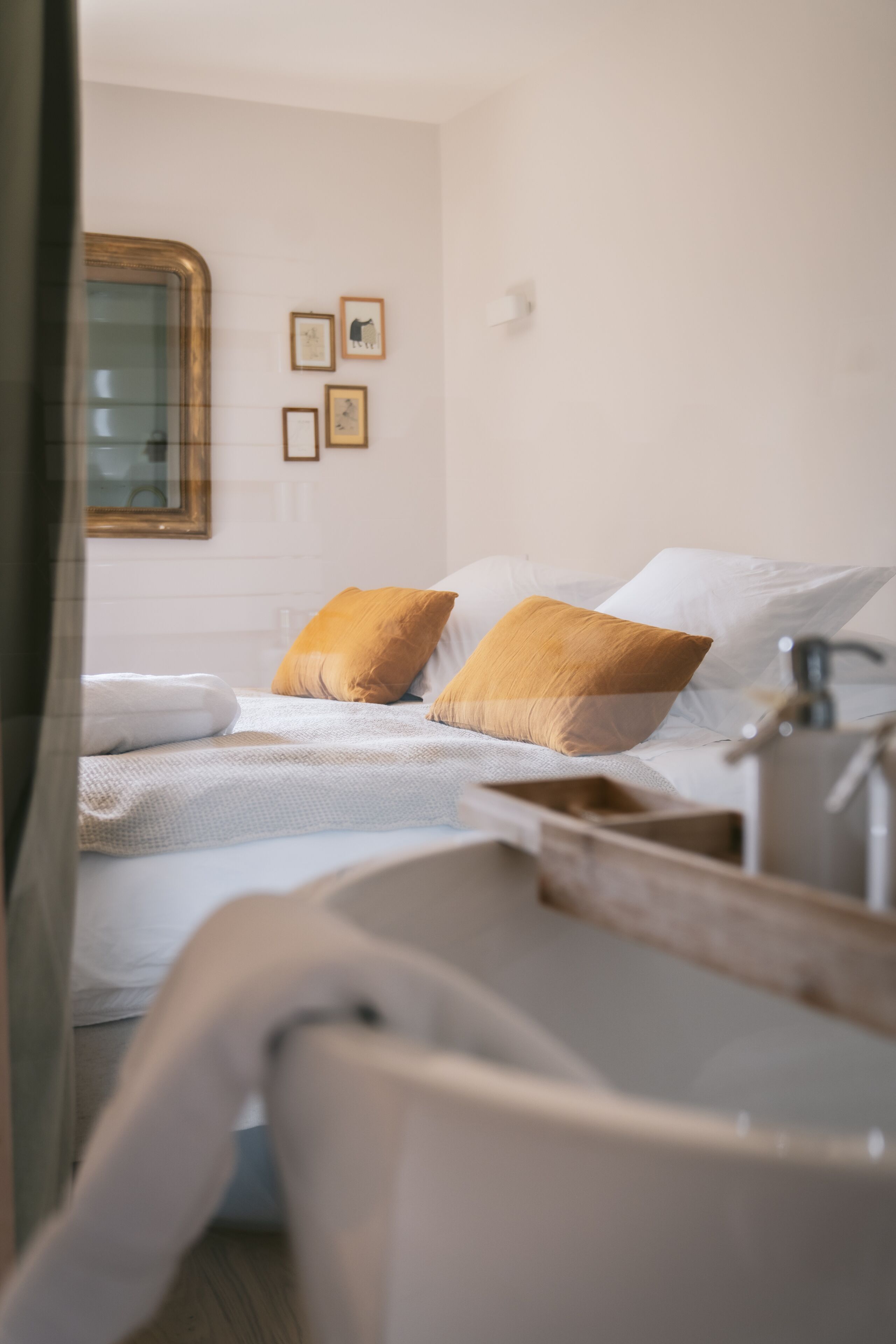 Un dormitorio con una cama, dos almohadas, una mesita de noche y un estante en la pared.