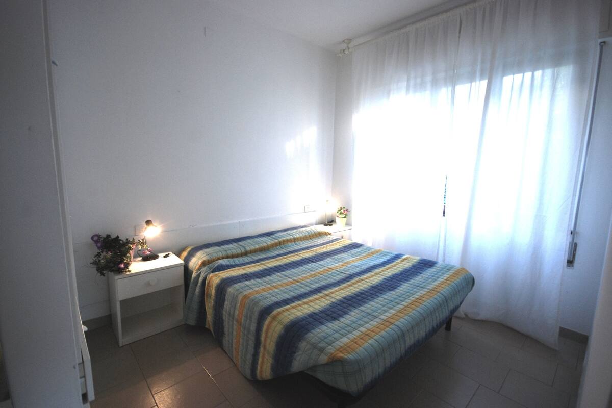Ein Schlafzimmer mit einem Bett, Nachttischen und einem Fenster mit Vorhängen.