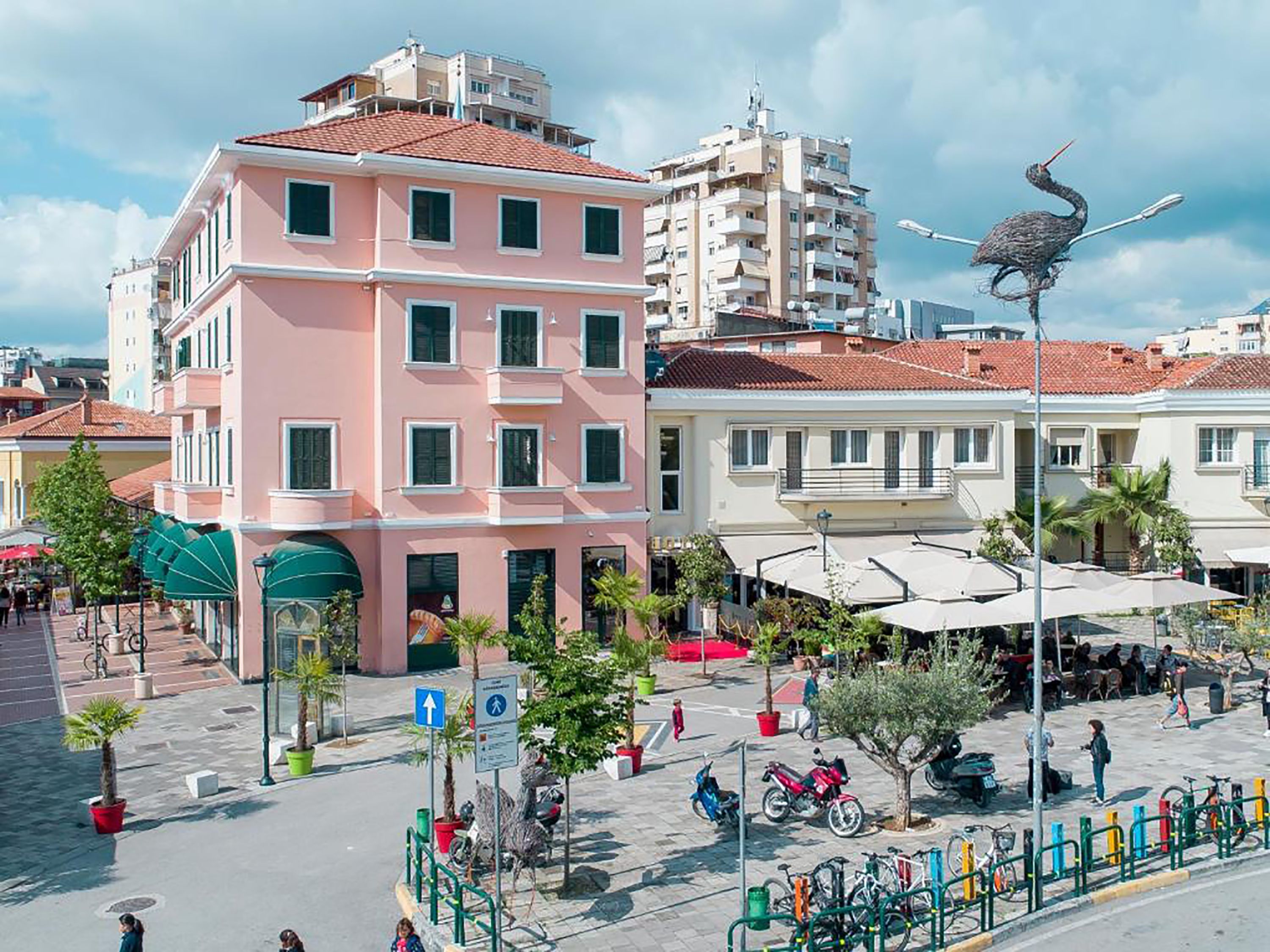 A multi-story building with a pink facade and a red-tiled roof.