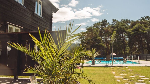Ein Holzhaus mit Swimmingpool, Rasen und blauem Himmel.
