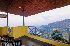 A balcony with a wooden ceiling, yellow walls, and blue railings. - Green n Breeze Resorts (Dehradun)