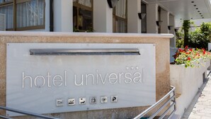 A hotel entrance with a sign reading "hotel universal" and symbols indicating amenities such as a pool, a restaurant, and parking. - Hotel Universal (Cattolica)