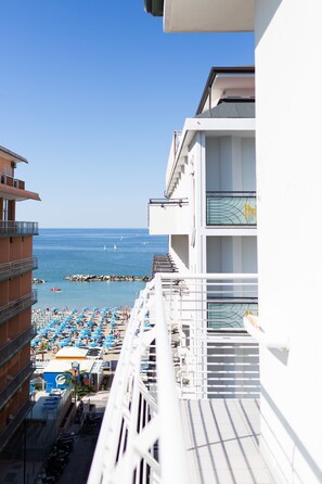 A hotel balcony overlooking a beach with sun loungers and a view of the sea. - Hotel Universal (Cattolica)