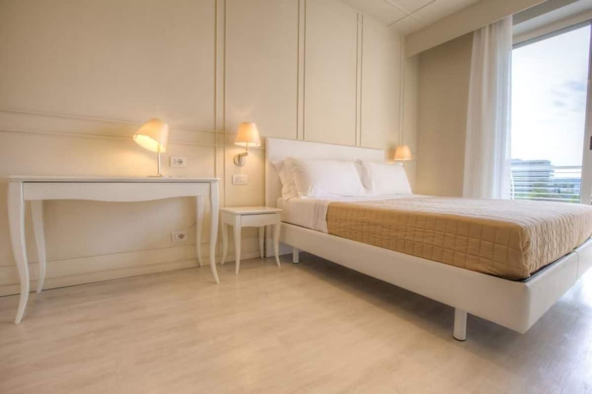 A bedroom with a bed, bedside tables, and lamps.