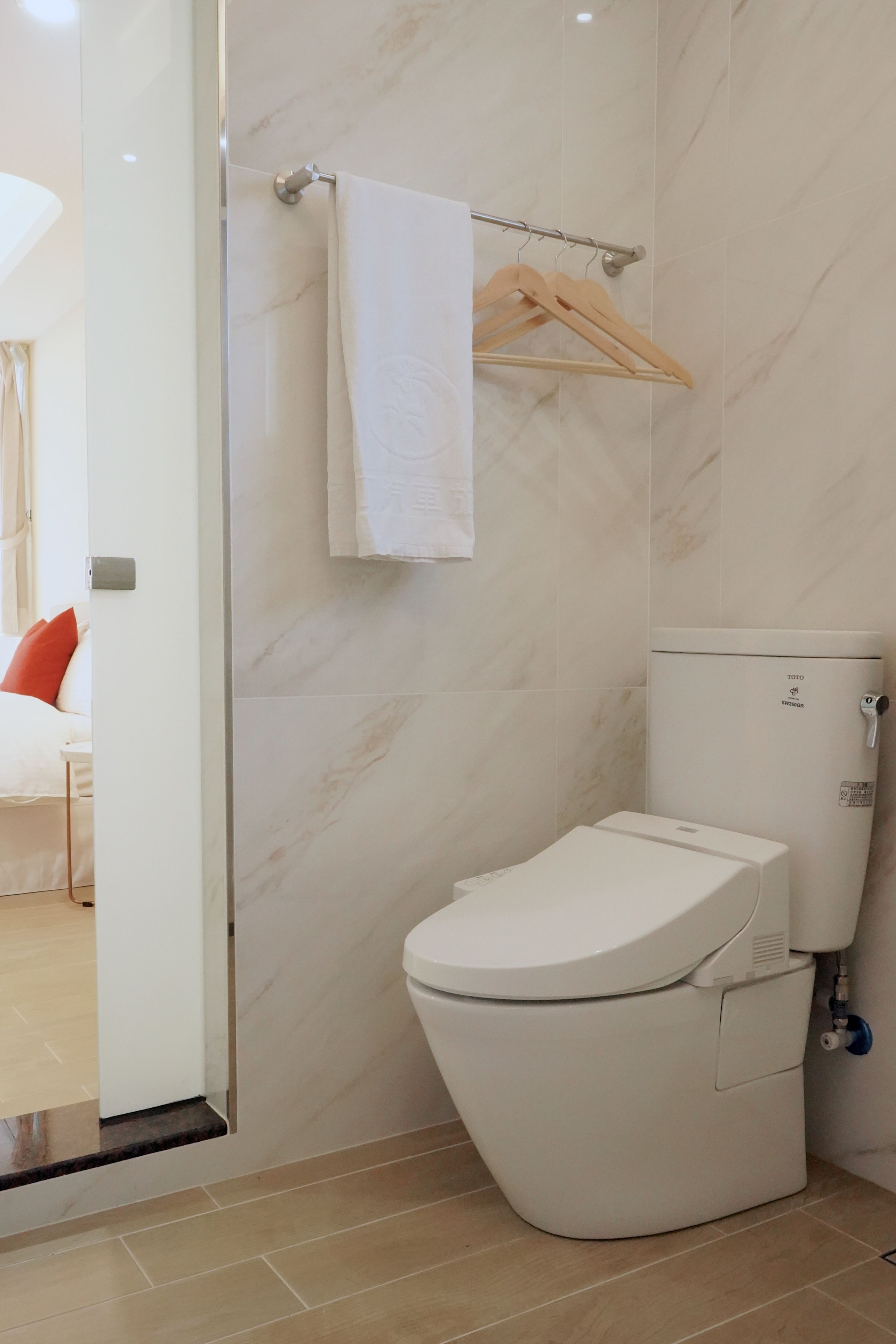 A modern bathroom with a toilet, a towel hanging on a rack, and a shower area.