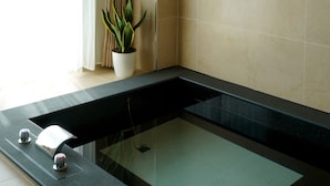 Une salle de bain moderne avec une baignoire entourée de parois en verre, une plante en pot et un espace douche.