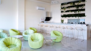 Une cuisine moderne avec un coin bar, des chaises rembourrées de couleur verte et un mur décoré de plantes.