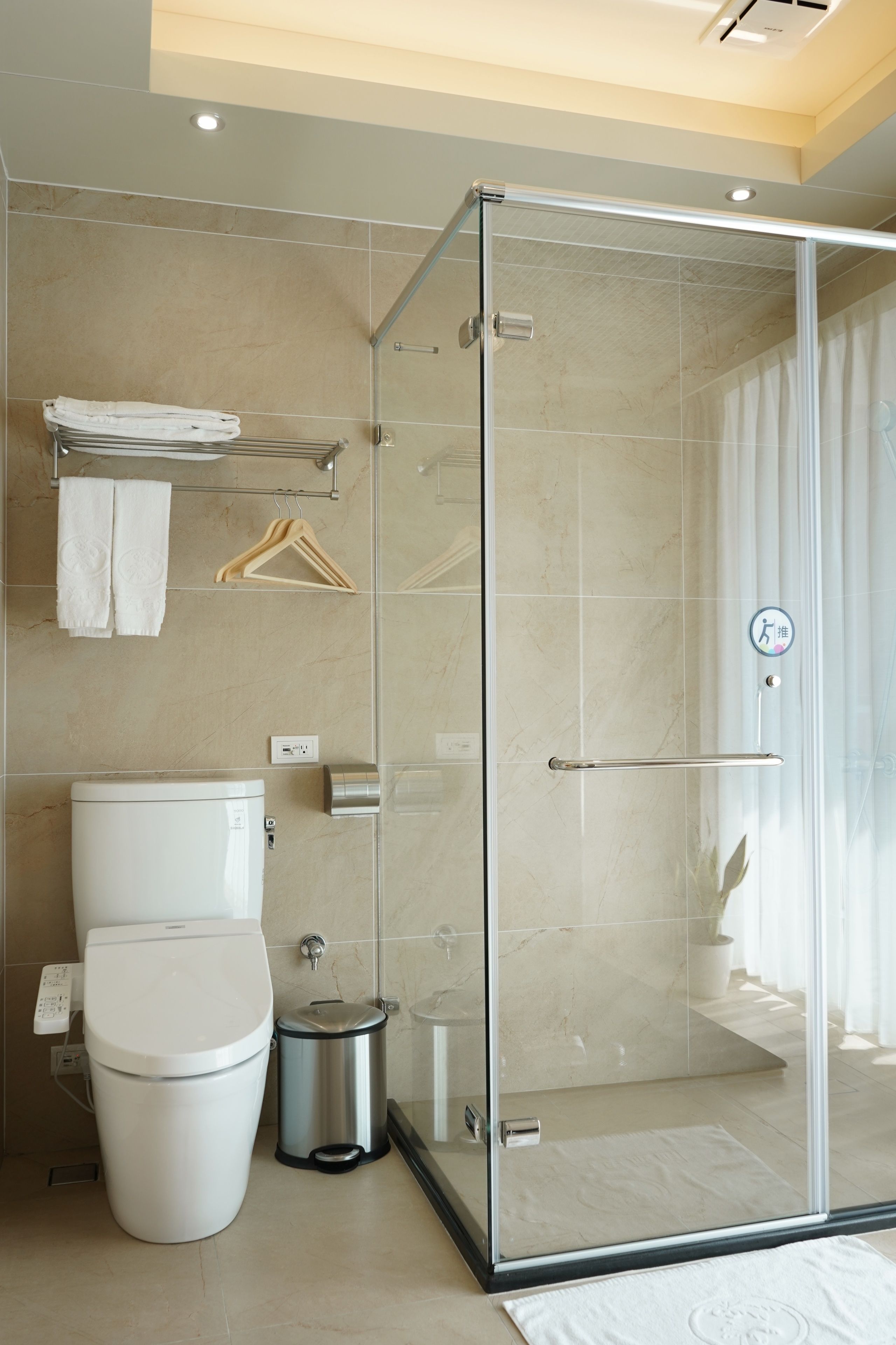 A modern bathroom with a glass-enclosed shower, a toilet, and a towel rack.