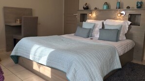 Un dormitorio con cama, mesita de noche, cómoda y un cuadro en la pared.