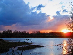 A sunset over a river with trees in the foreground and a cloudy sky. - Chambres d'Hotes Penker (Minihy-Treguier)