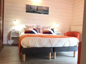 A neatly arranged bedroom with a bed, two bedside tables with lamps, a chair, and a painting of a lighthouse on the wall. - Chambres d'Hotes Penker (Minihy-Treguier)