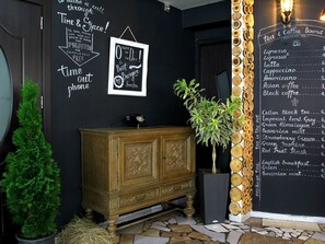 A cozy cafe interior with a chalkboard menu listing various drinks and a decorative sign above the counter. - Cron Palace Tbilisi (T'bilisi)