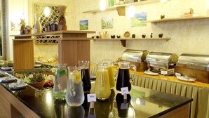 Zona de bufé con diversas opciones de comida y bebida, incluyendo frutas, ensaladas y refrescos.