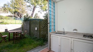 A small outdoor kitchen with a sink and a table with chairs, a wooden fence, and a tree in the background. - N151 - Numana, delightful two-room apartment with porch (Numana)