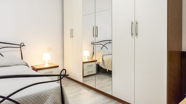 A bedroom with a bed, bedside table, lamp, and a wardrobe with mirrored doors. - N151 - Numana, delightful two-room apartment with porch (Numana)